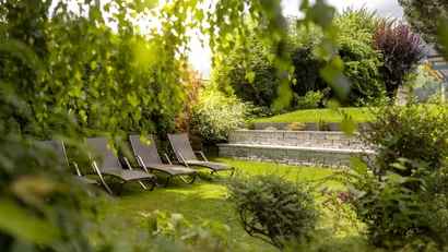 Vier Liegestühle auf grünem Rasen in einem sonnigen Garten