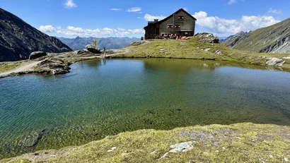 Alpenhütte am Bergsee unter blauem Himmel