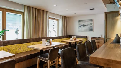 Gemütlicher Essbereich mit Holztischen und Ledersesseln in hellem Raum