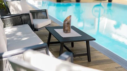 Sitzgruppe mit Tisch und Kerze neben einem Pool