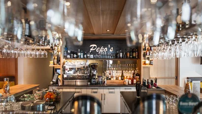 Moderne Bar mit Gläsern und Spirituosen hinter der Theke bei Pepo's