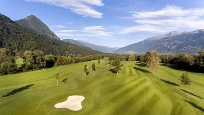 Golfplatz mit Bergen und blauem Himmel im Hintergrund