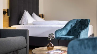 Gemütliche Sitzecke mit blauem Sessel und Bett im Hintergrund