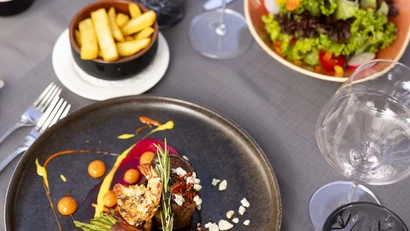 Gourmetgericht mit grünem Gemüse, Garnelen, Salat und Pommes auf Tisch