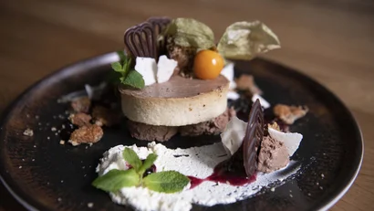 Elegantes Dessert mit Schokolade, Beeren und Minze auf dunklem Teller