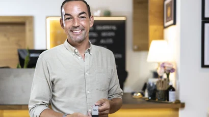 Lächelnder Mann hält Hotelschlüssel Nummer 107 an der Rezeption