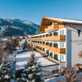 Hotel Moarhof umgeben von verschneiter Winterlandschaft und Bergen im Hintergrund