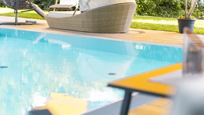 Gemütliche Poolterrasse mit Liegestühlen und Hängesessel im Garten