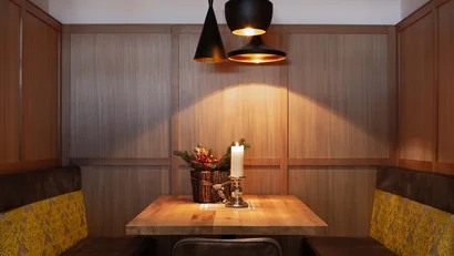 Holztisch mit Kerze und Weihnachtsdeko unter drei schwarzen Hängeleuchten