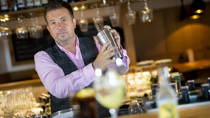 Barkeeper schüttelt Cocktailmixer an einer Bar