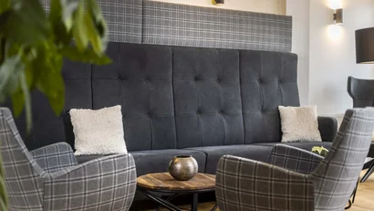 Moderne Sitzecke mit karierten Sesseln und dunkler Couch, Holztisch und Kissen