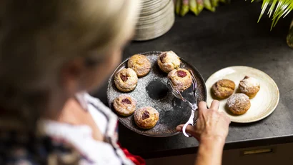 Frau legt Muffins mit Zange auf Teller auf der Küchenarbeitsplatte