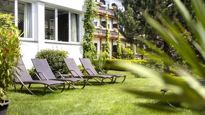 Liegestühle auf grünem Rasen neben einem Gebäude mit Kletterpflanzen