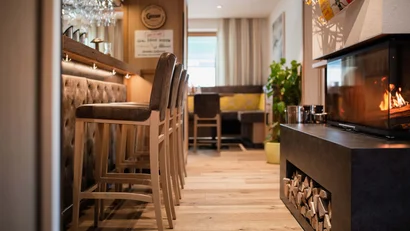 Bar mit hohen Stühlen und modernem Kamin in gemütlichem Raum