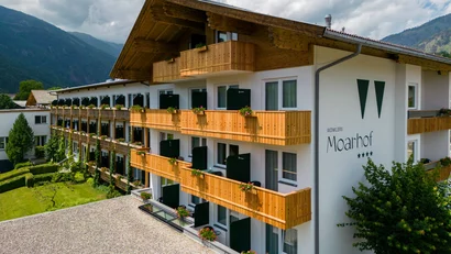 Mehrstöckiges Hotel Moarhof mit Holzbalkonen in Berglandschaft